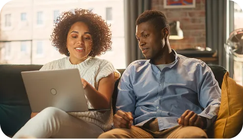 man and woman sitting on couch looking at a laptop